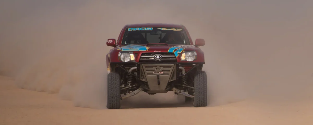 Motor sports desert racing photography showing a vehicle racing through sand dunes in Dubai, UAE by IBN Films