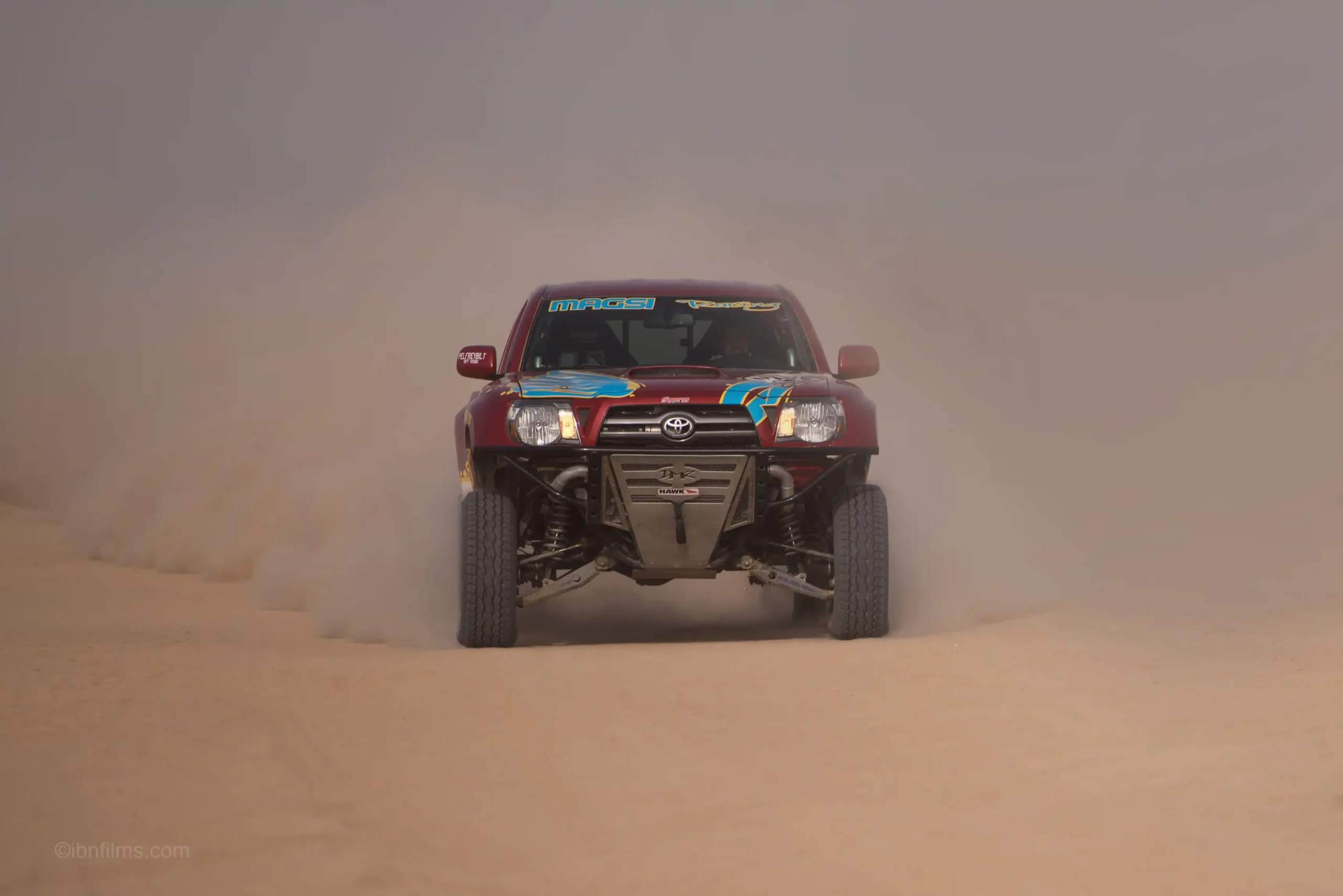 Motor sports desert racing photography showing a vehicle racing through sand dunes in Dubai, UAE by IBN Films