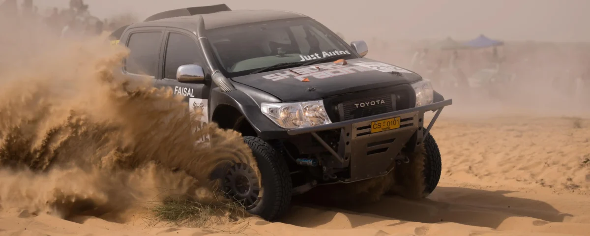 Off-road motor sports photography capturing a vehicle racing through desert terrain in Dubai, UAE by IBN Films
