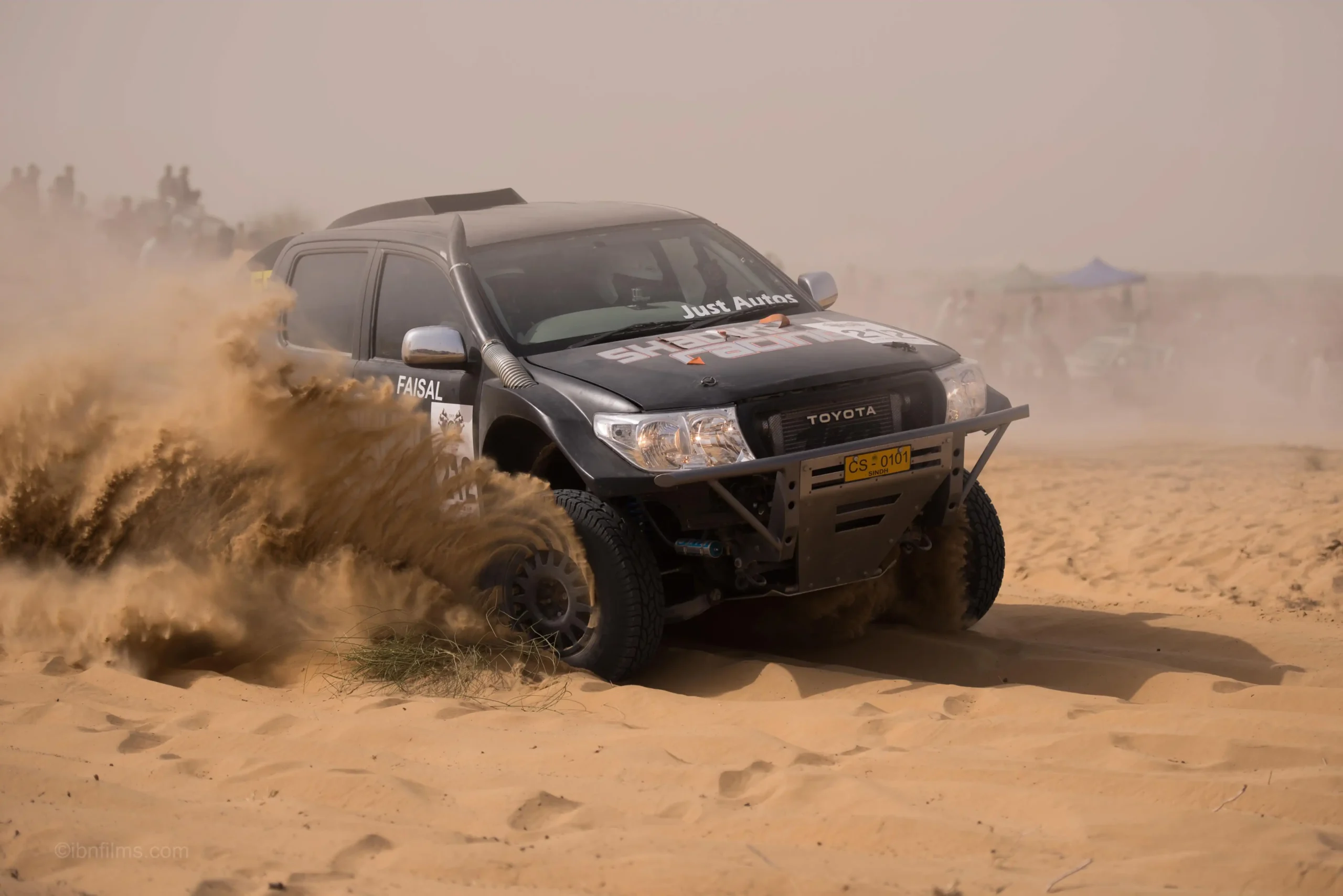 Off-road motor sports photography capturing a vehicle racing through desert terrain in Dubai, UAE by IBN Films
