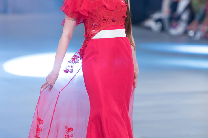 Model wearing a red evening gown walking on a fashion runway in Dubai, UAE, photographed by IBN Films