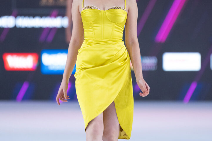 Model walking the runway in a yellow dress during a fashion show in Dubai, photographed by IBN Films.